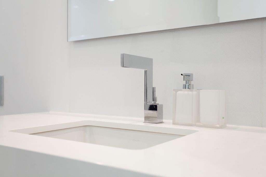A bathroom sink with a soap dispenser and a mirror.