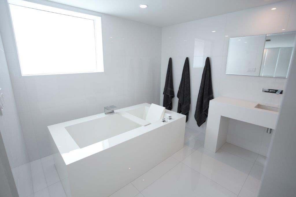 A bathroom with a bathtub , sink , mirror and window.