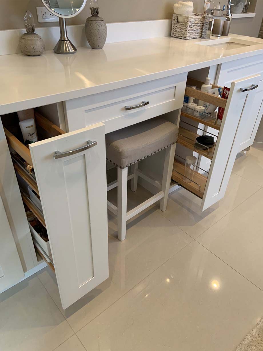A bathroom vanity with a stool and drawers open.
