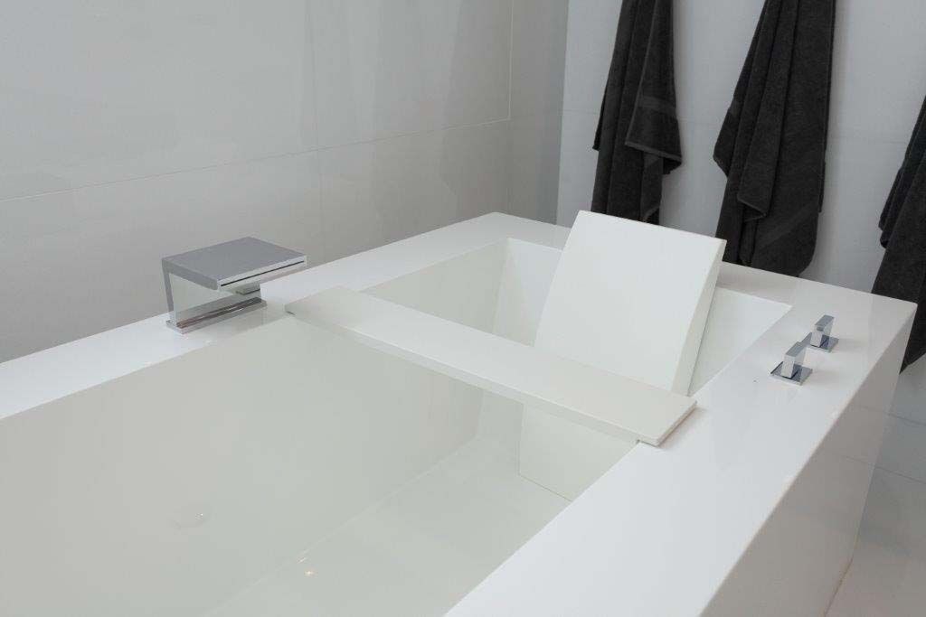 A white bathtub in a bathroom with black towels hanging on the wall.