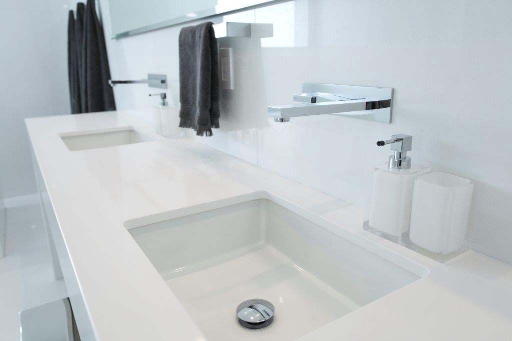 A bathroom with two sinks and a soap dispenser.