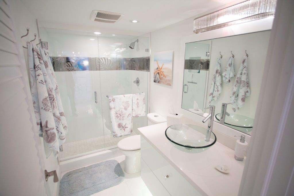 A bathroom with a sink , toilet , shower and mirror.