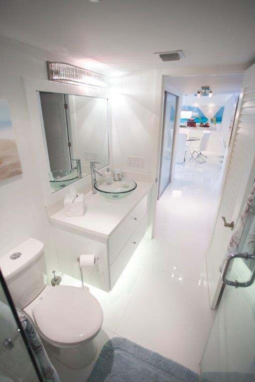 A bathroom with a toilet , sink and mirror.