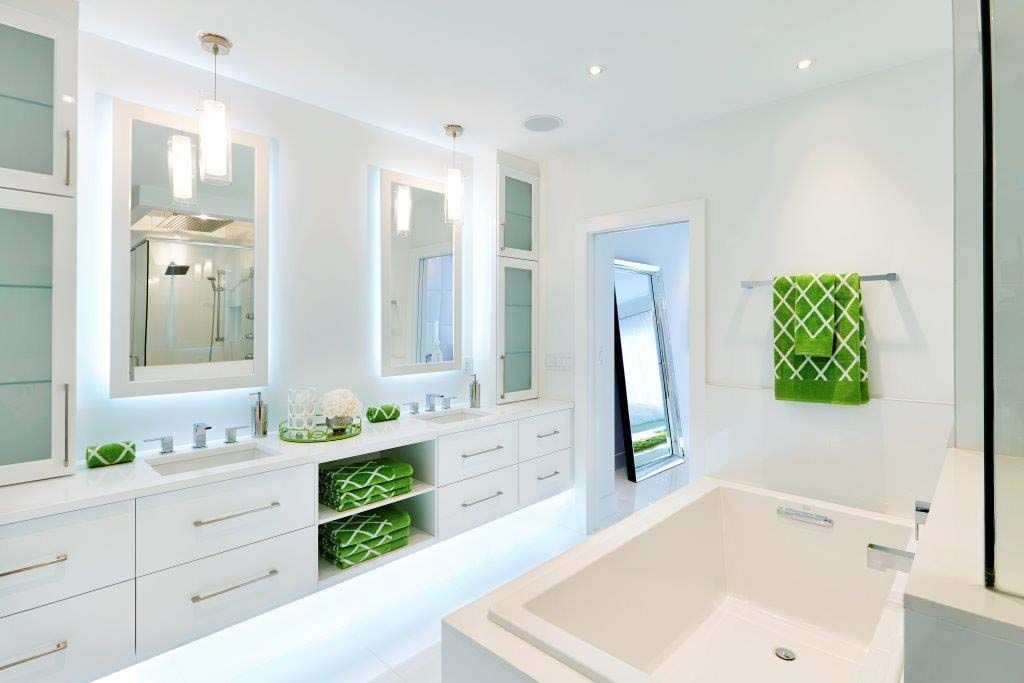A bathroom with a bathtub , sinks , mirrors and green towels.