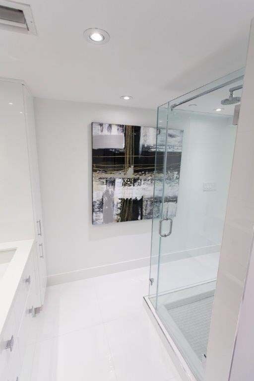 A bathroom with a walk in shower and a painting on the wall.