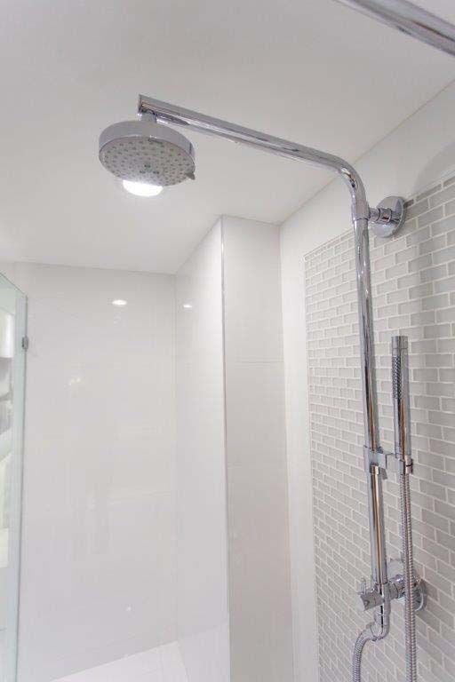 A shower head is hanging from the ceiling in a bathroom.