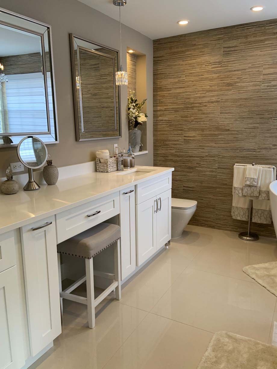 A bathroom with white cabinets , a toilet , a sink and a mirror.