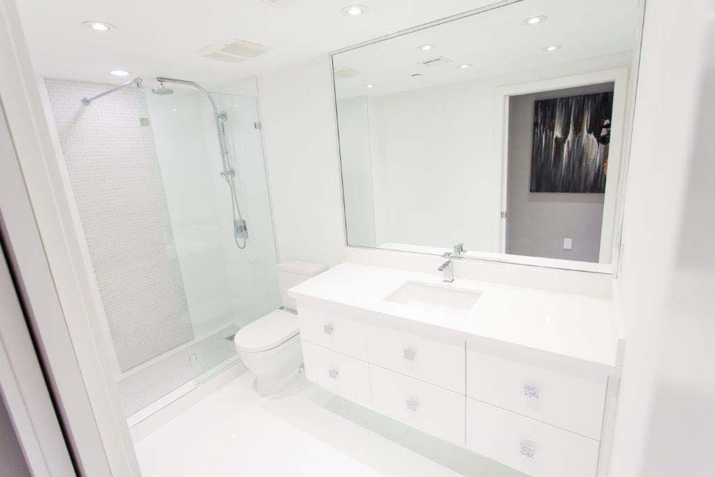A bathroom with a sink , toilet , shower and mirror.