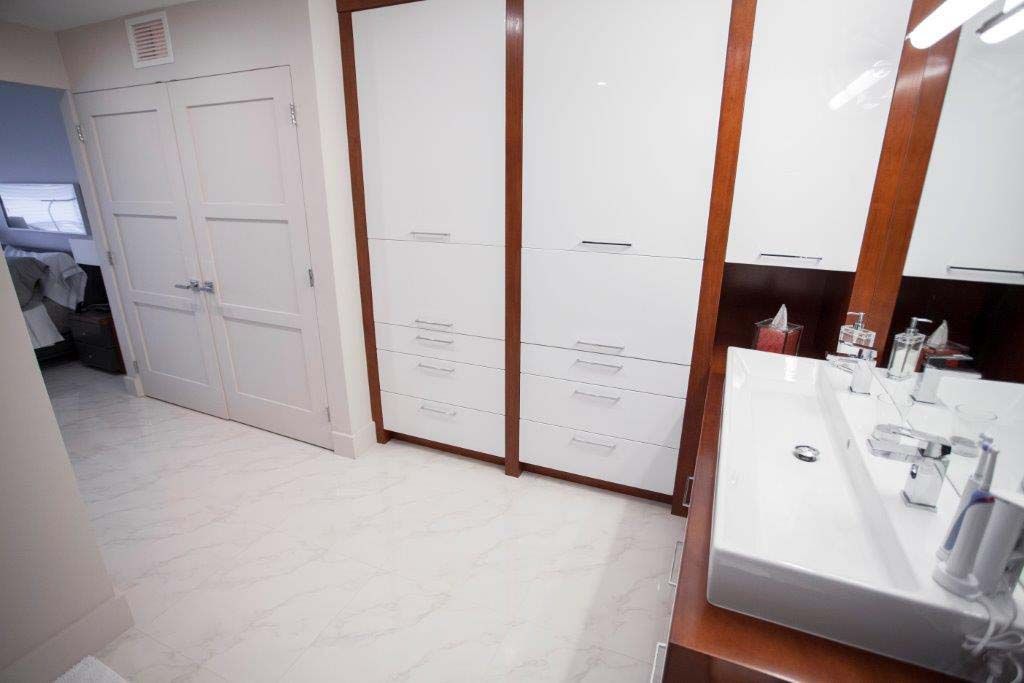 A bathroom with a sink , mirror and closets