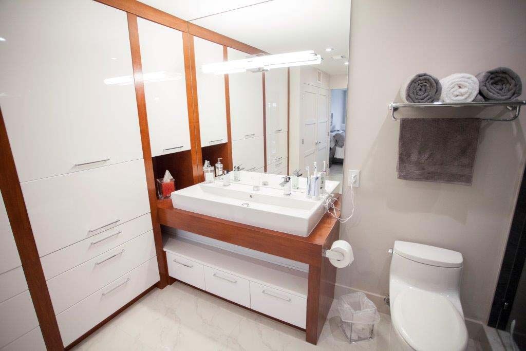 A bathroom with two sinks , a toilet and a mirror.