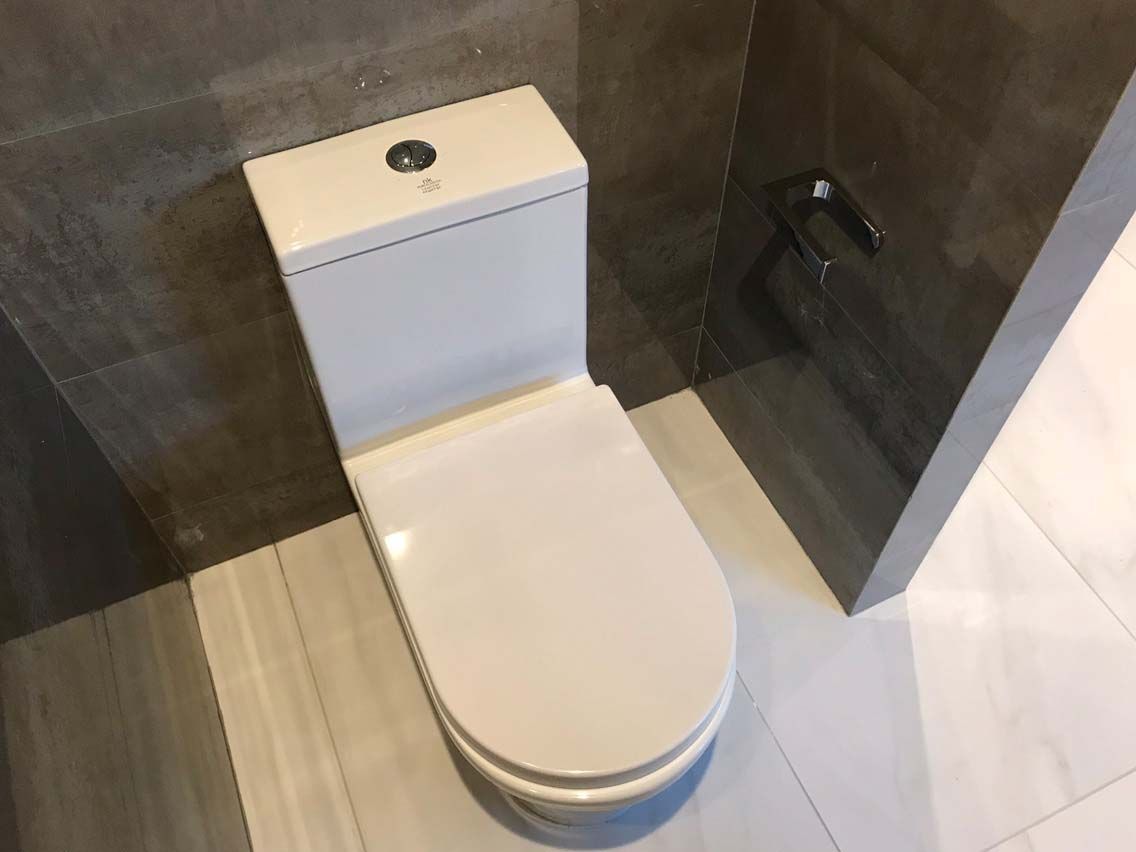 A white toilet is sitting in a bathroom next to a wall.