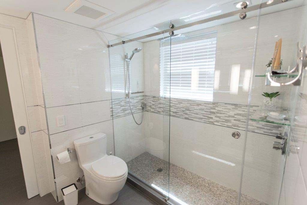 A bathroom with a toilet , shower and sliding glass doors.