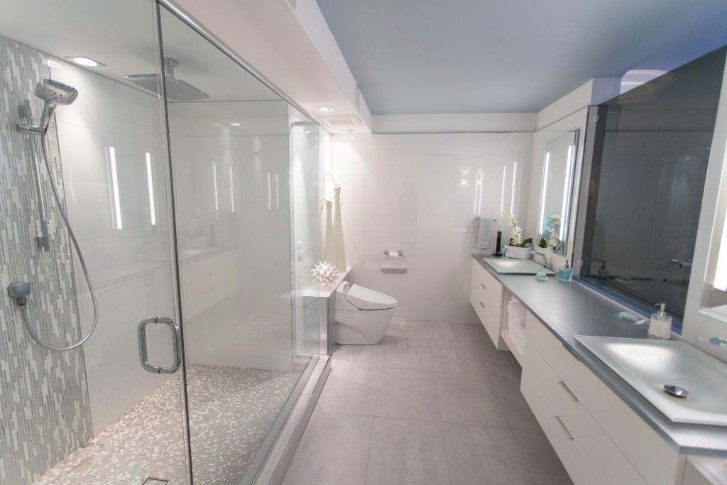 A bathroom with a walk in shower , sink and toilet.