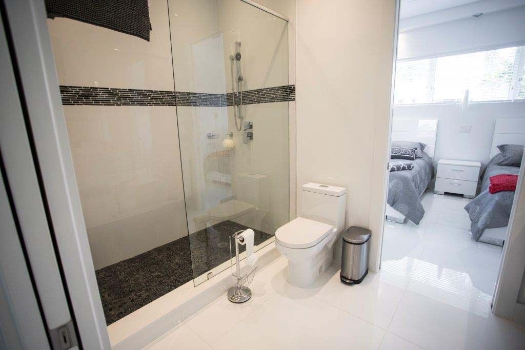 A bathroom with a toilet , shower and two beds.