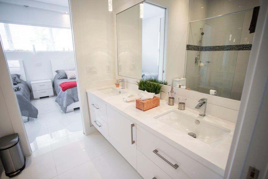 A bathroom with two sinks , a mirror and a walk in shower.