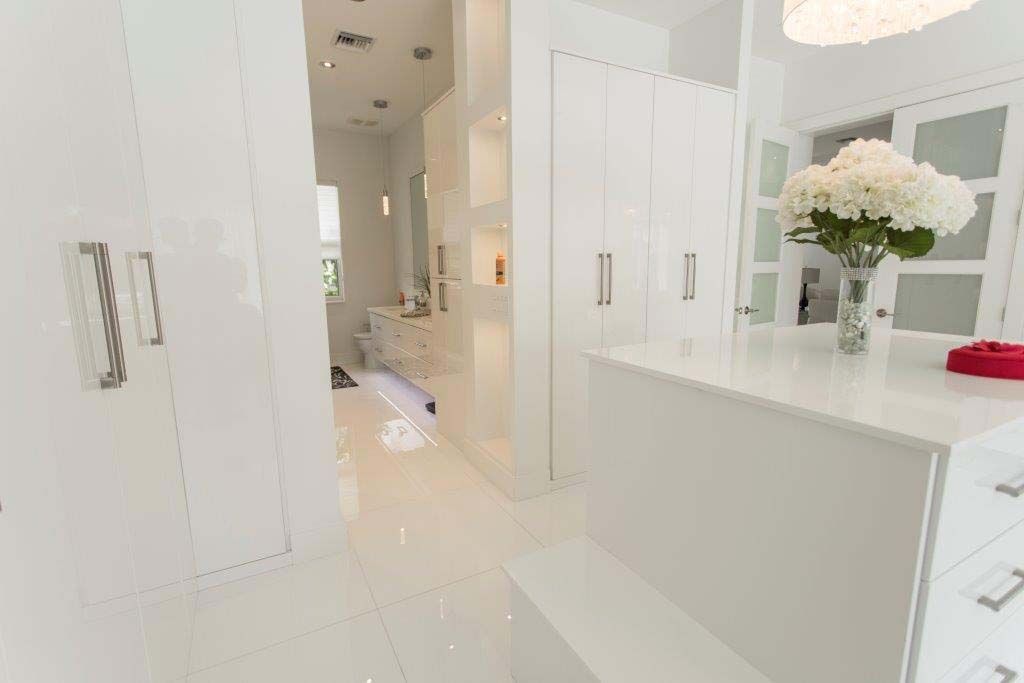 A white kitchen with a vase of flowers on the counter.