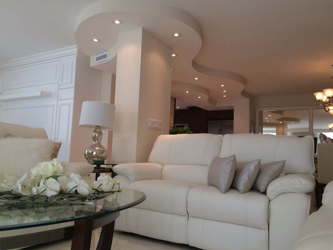 A living room with white furniture and a glass coffee table