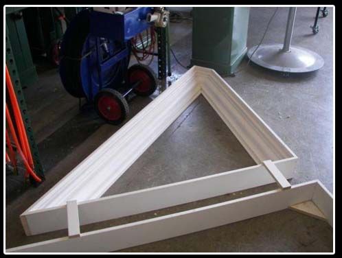 A triangle shaped piece of wood is sitting on a concrete floor.