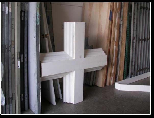 A white cross is sitting in a room surrounded by wooden boards