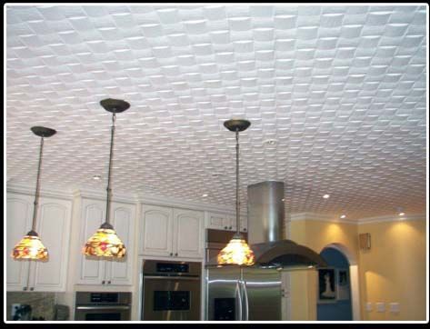 A kitchen with a white tiled ceiling and three lamps hanging from it