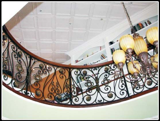 A staircase with a wrought iron railing and a chandelier hanging from the ceiling