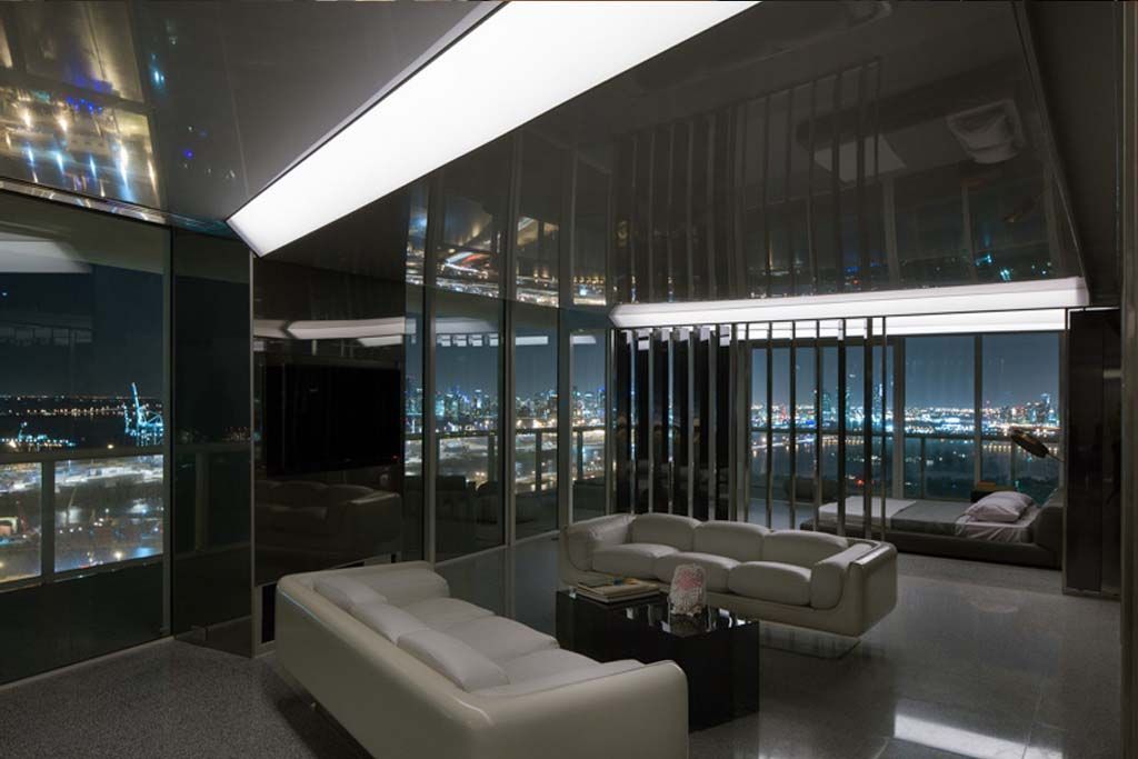 A living room with a couch and a table with a view of the city at night.