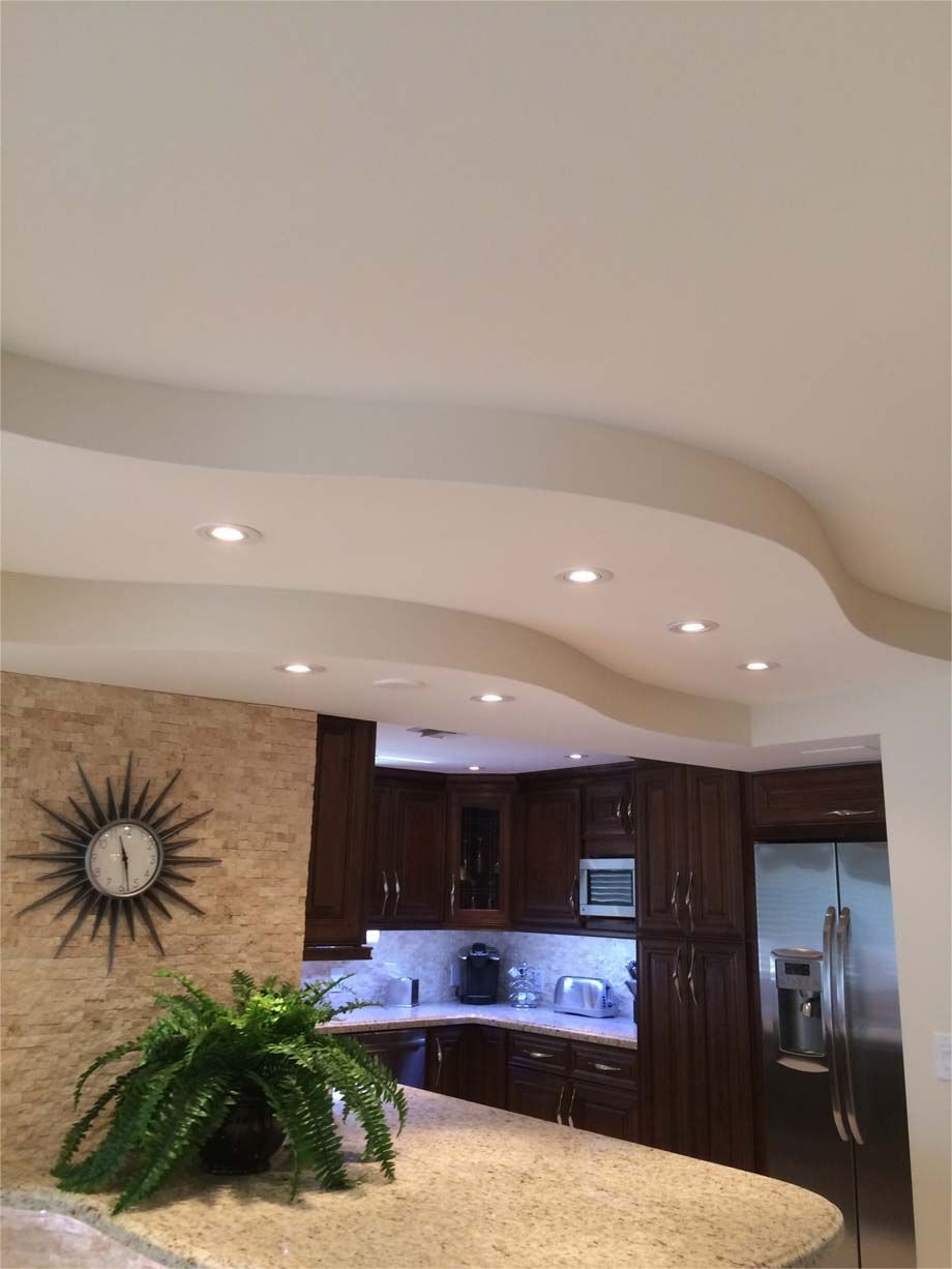 A kitchen with a clock on the wall and a plant on the counter