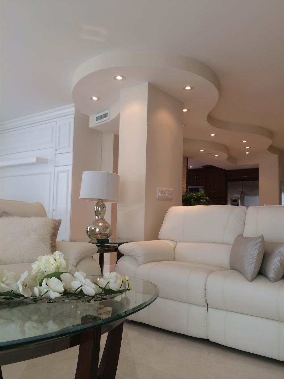 A living room with white furniture and a glass coffee table