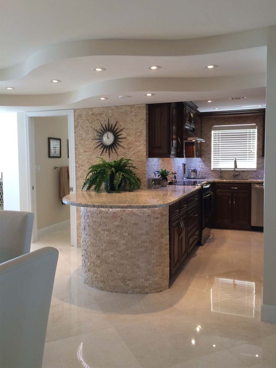 A kitchen with a large island and a clock on the wall.
