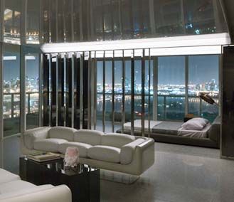 A living room with a couch and a bed with a view of the city at night.