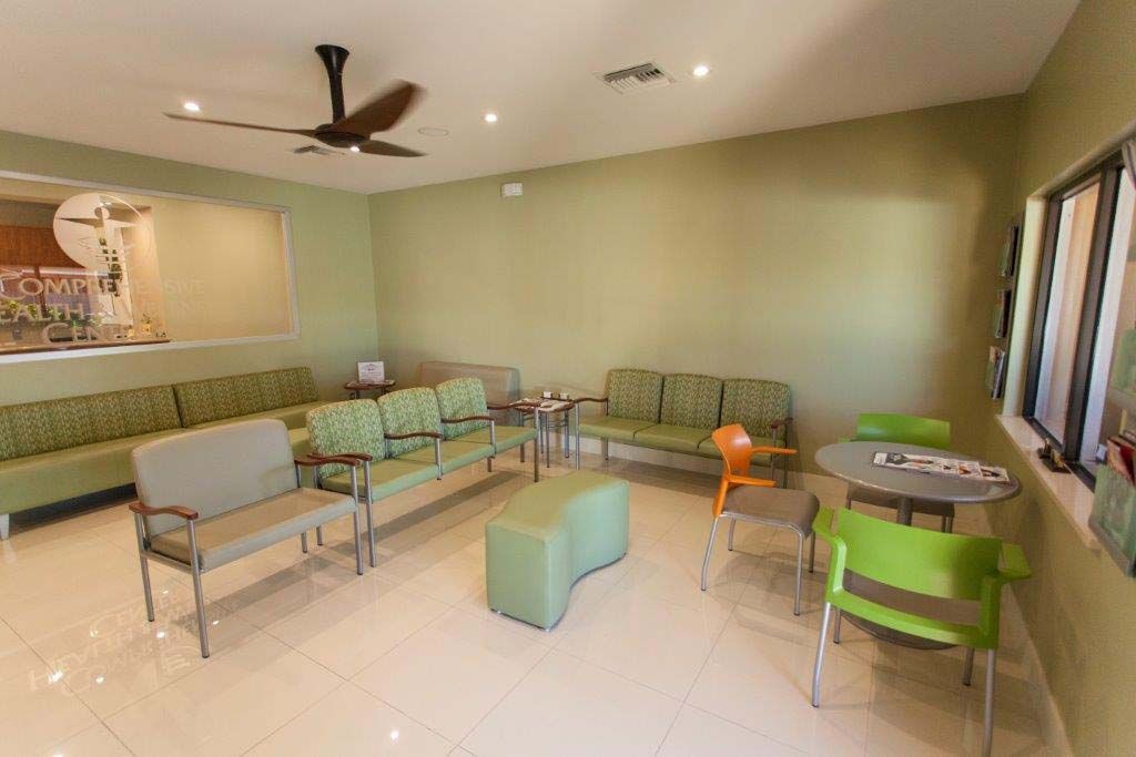 A waiting room with green chairs and a ceiling fan.