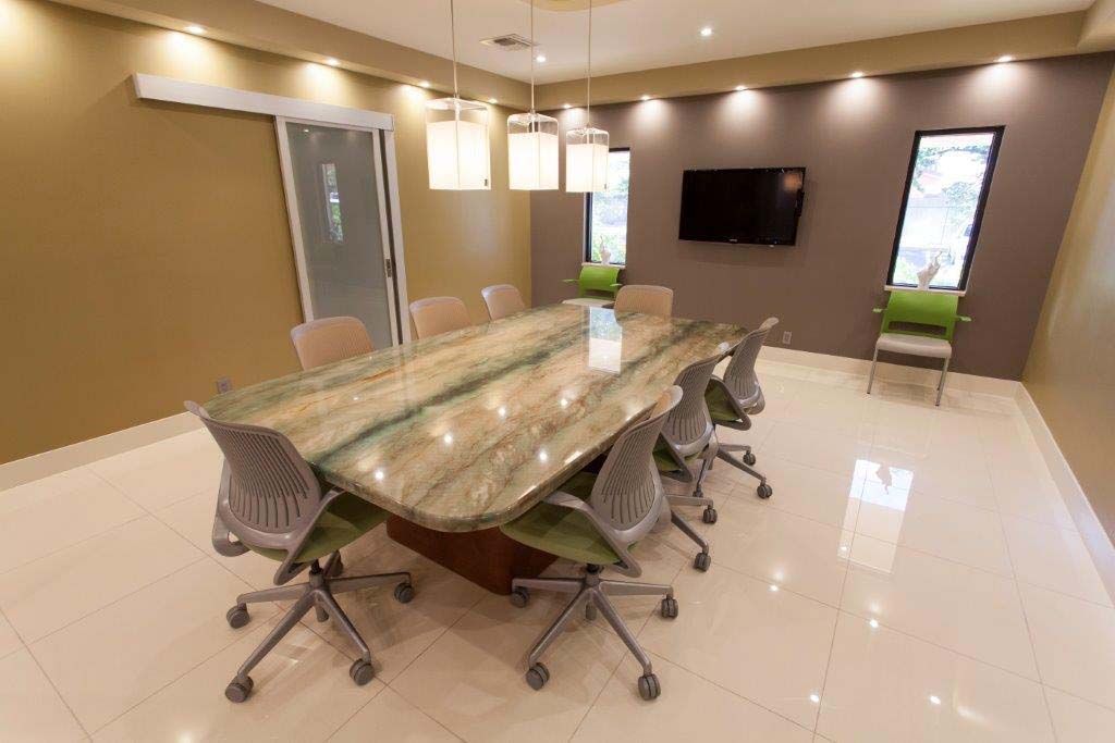 A conference room with a long table and chairs and a flat screen tv.