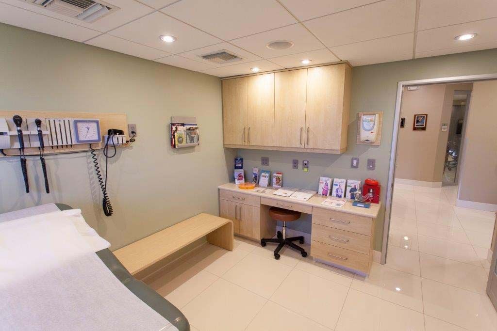 A doctor 's office with a desk and a stethoscope on the wall.