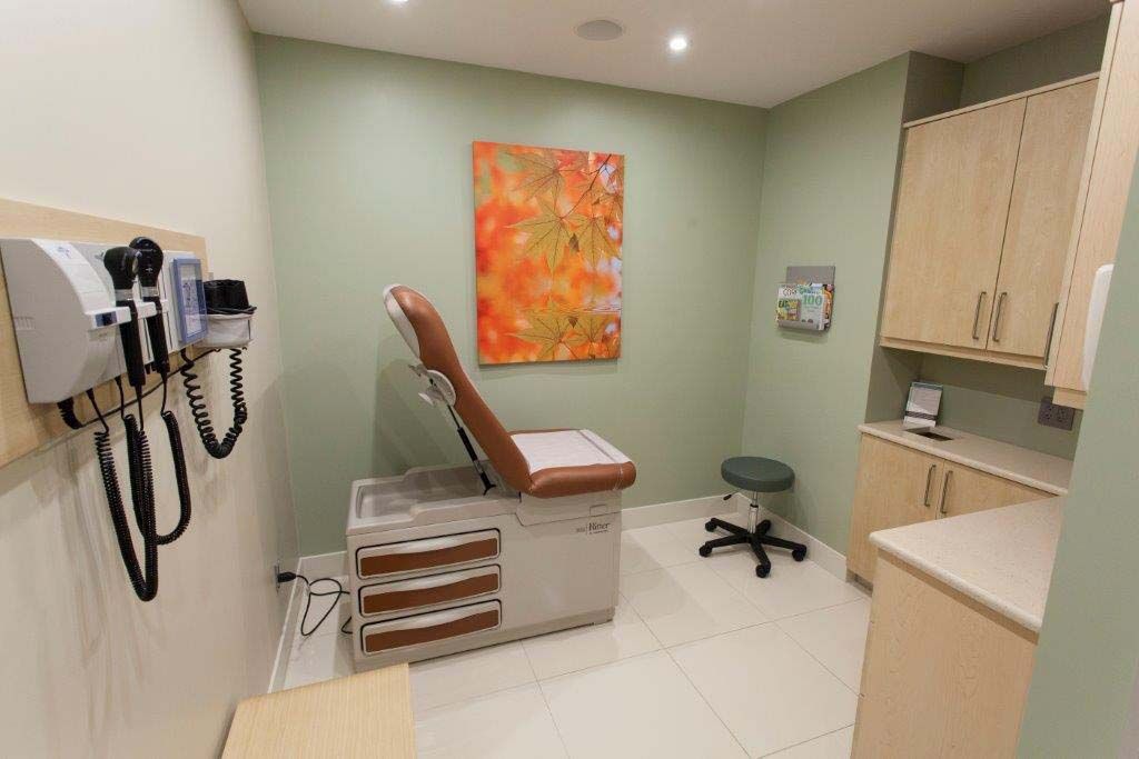 A doctor 's office with a painting on the wall and a stool.