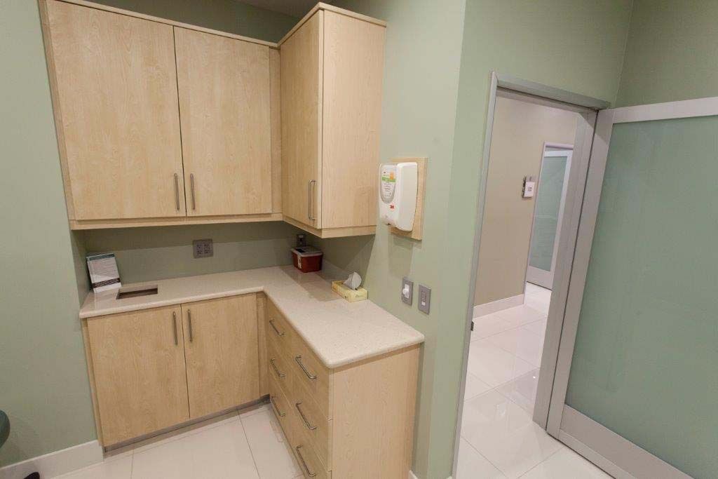 A kitchen with wooden cabinets and a door leading to a bathroom.
