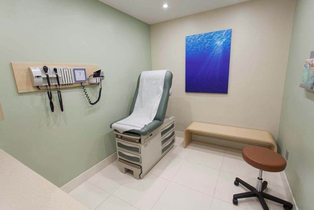 A doctor 's office with a chair and a bench.