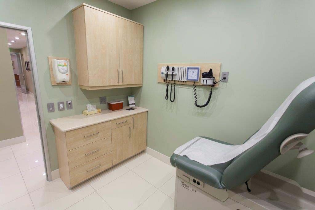 A doctor 's office with a chair and a stethoscope on the wall.