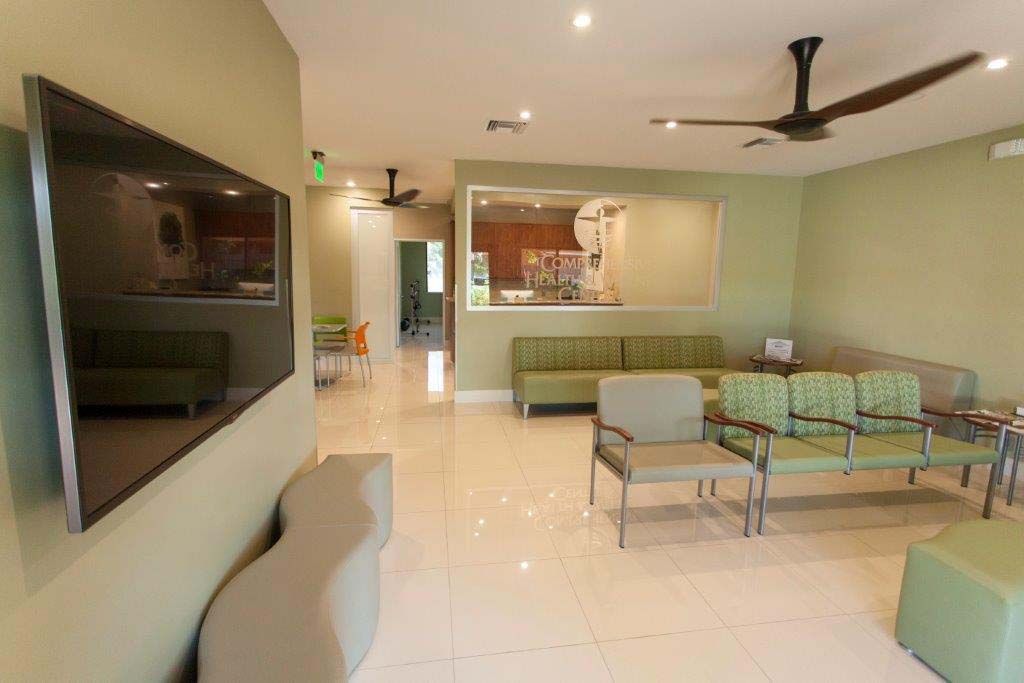 A waiting room with a flat screen tv and a ceiling fan.