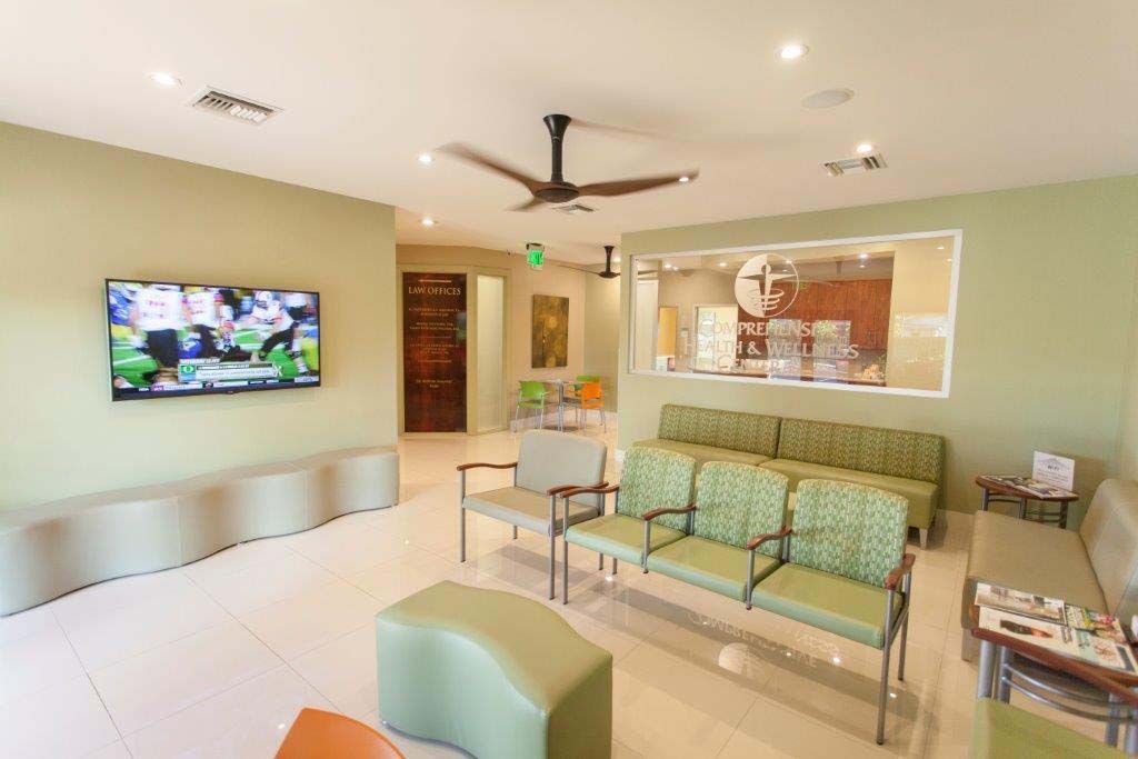 A waiting room with green chairs and a flat screen tv on the wall.