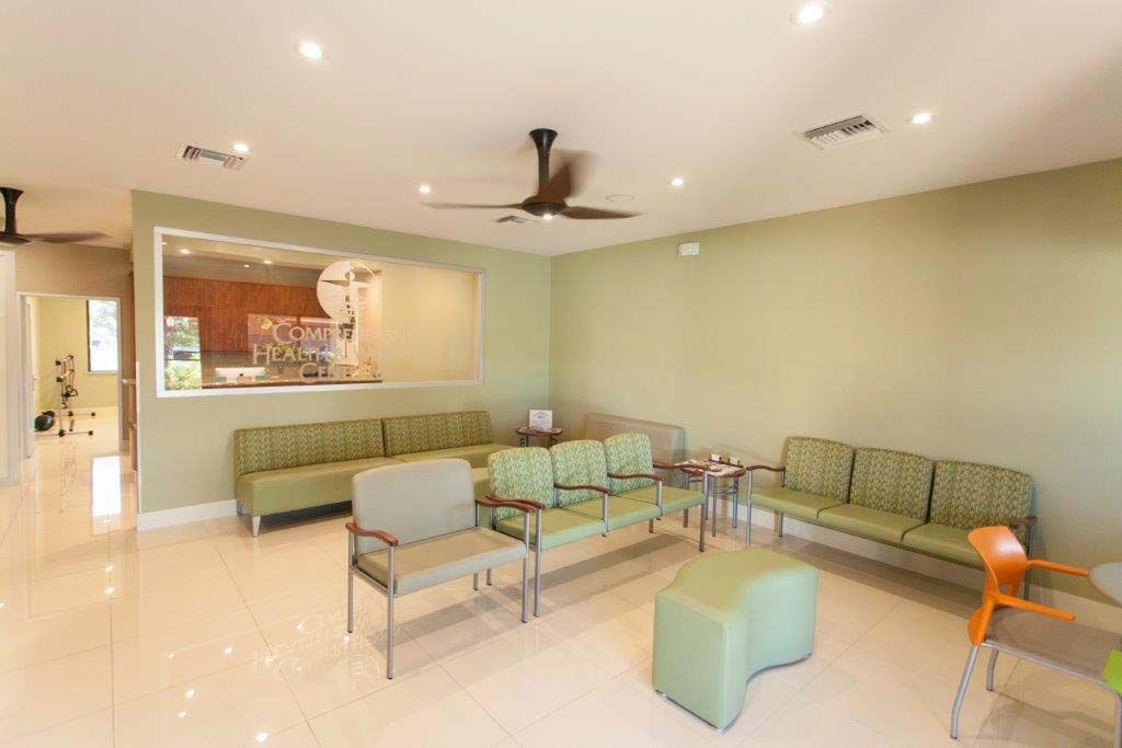 A waiting room with green chairs and a ceiling fan.
