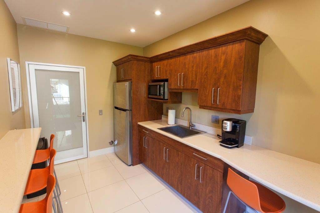 A kitchen with wooden cabinets , stainless steel appliances , a refrigerator and a sink.