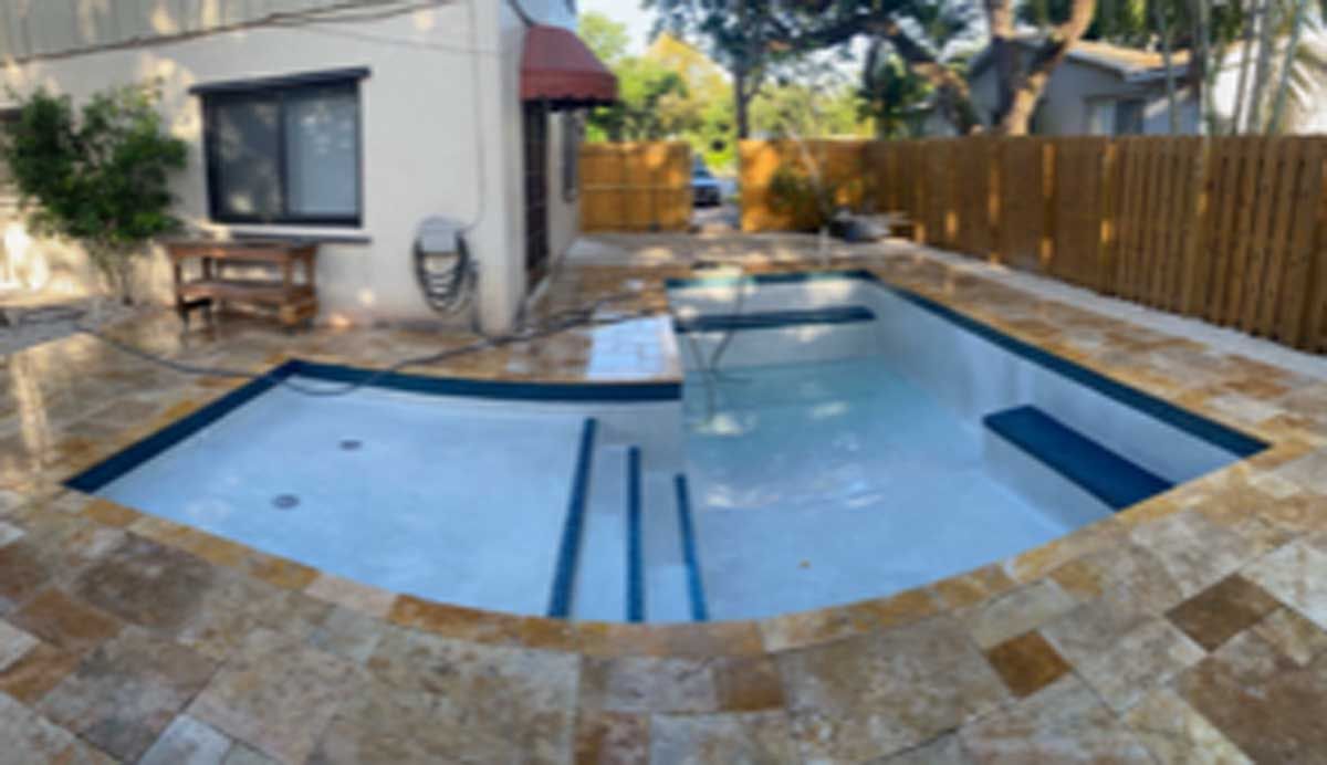 A large swimming pool is in the backyard of a house.