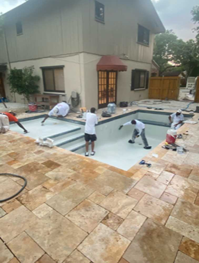 A group of people are working on a swimming pool in front of a house.