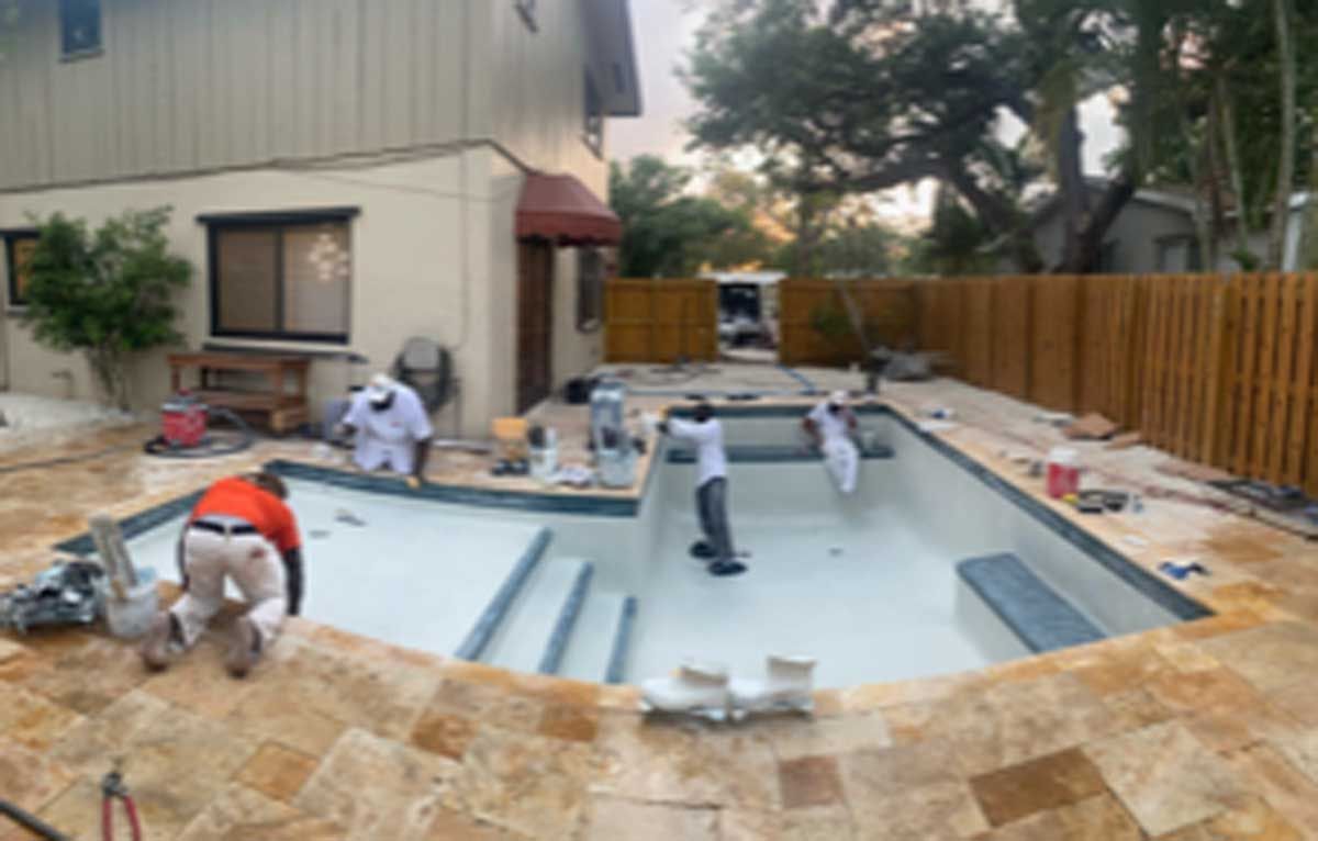 A swimming pool is being built in the backyard of a house