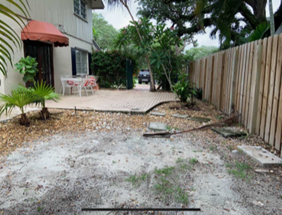 A backyard with a wooden fence and a patio.