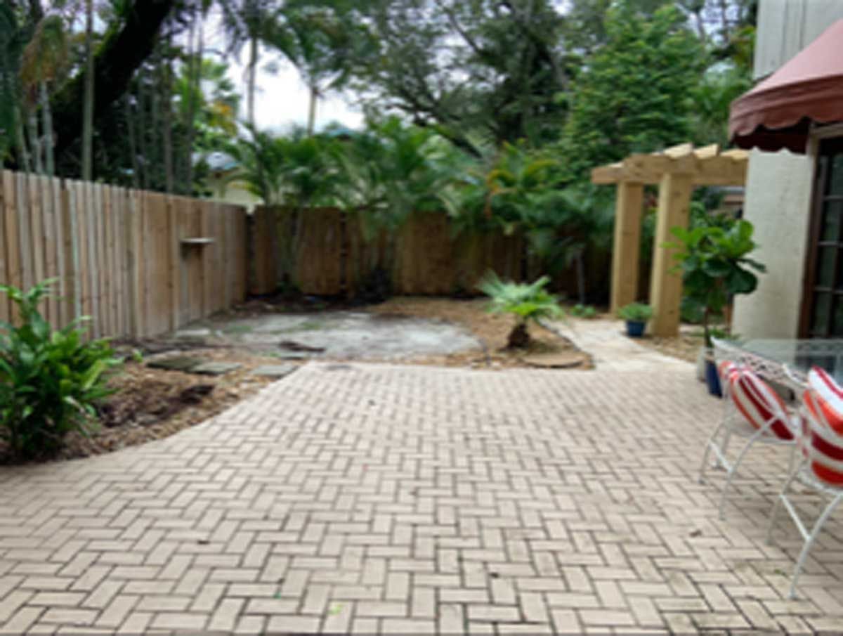 A backyard with a brick patio and a wooden fence