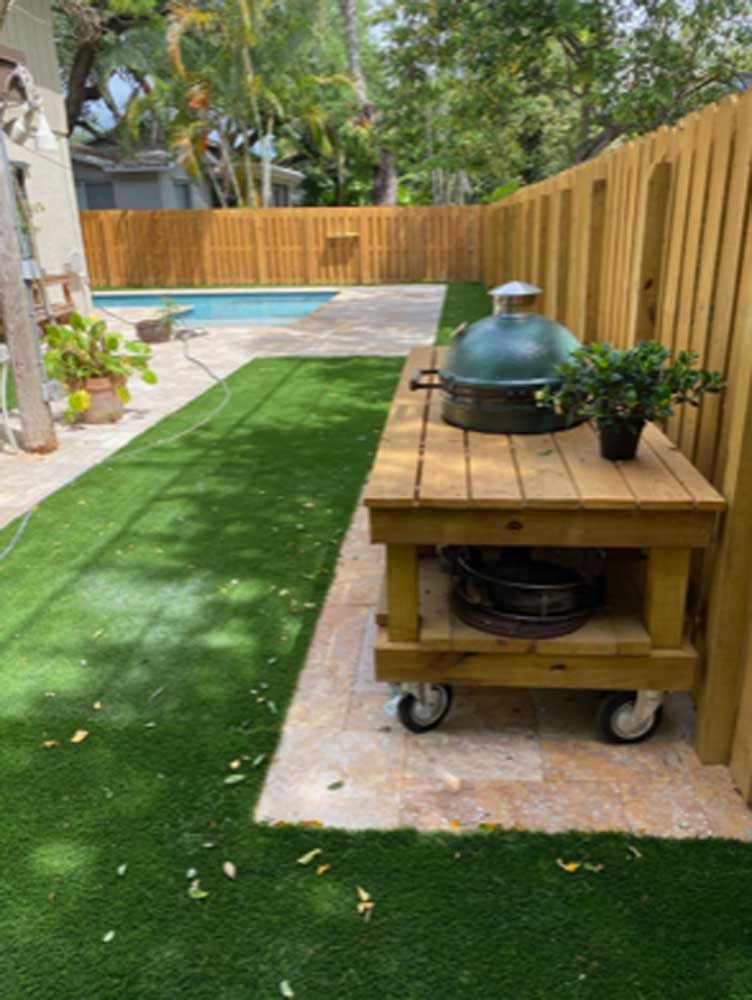 A wooden table with a grill on top of it in a backyard.