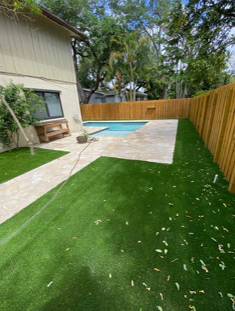 A backyard with a wooden fence and a swimming pool.