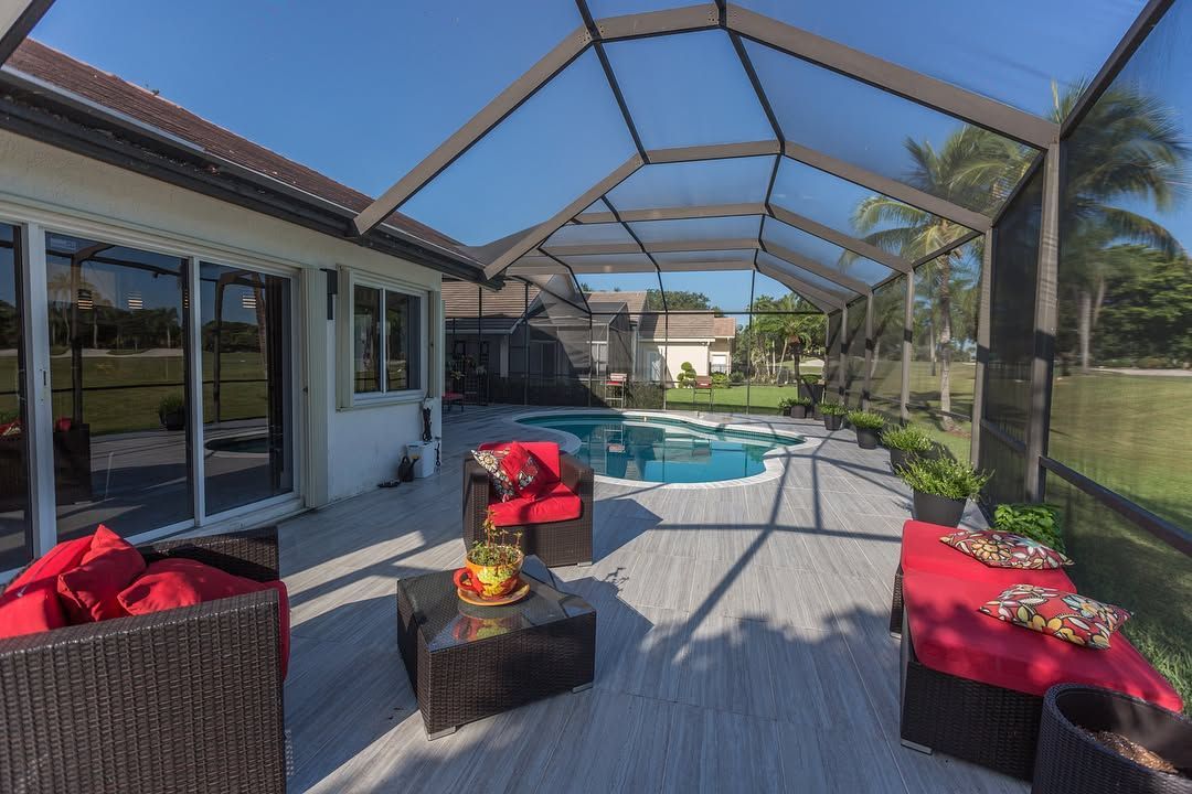 A screened in patio with a swimming pool in the background.