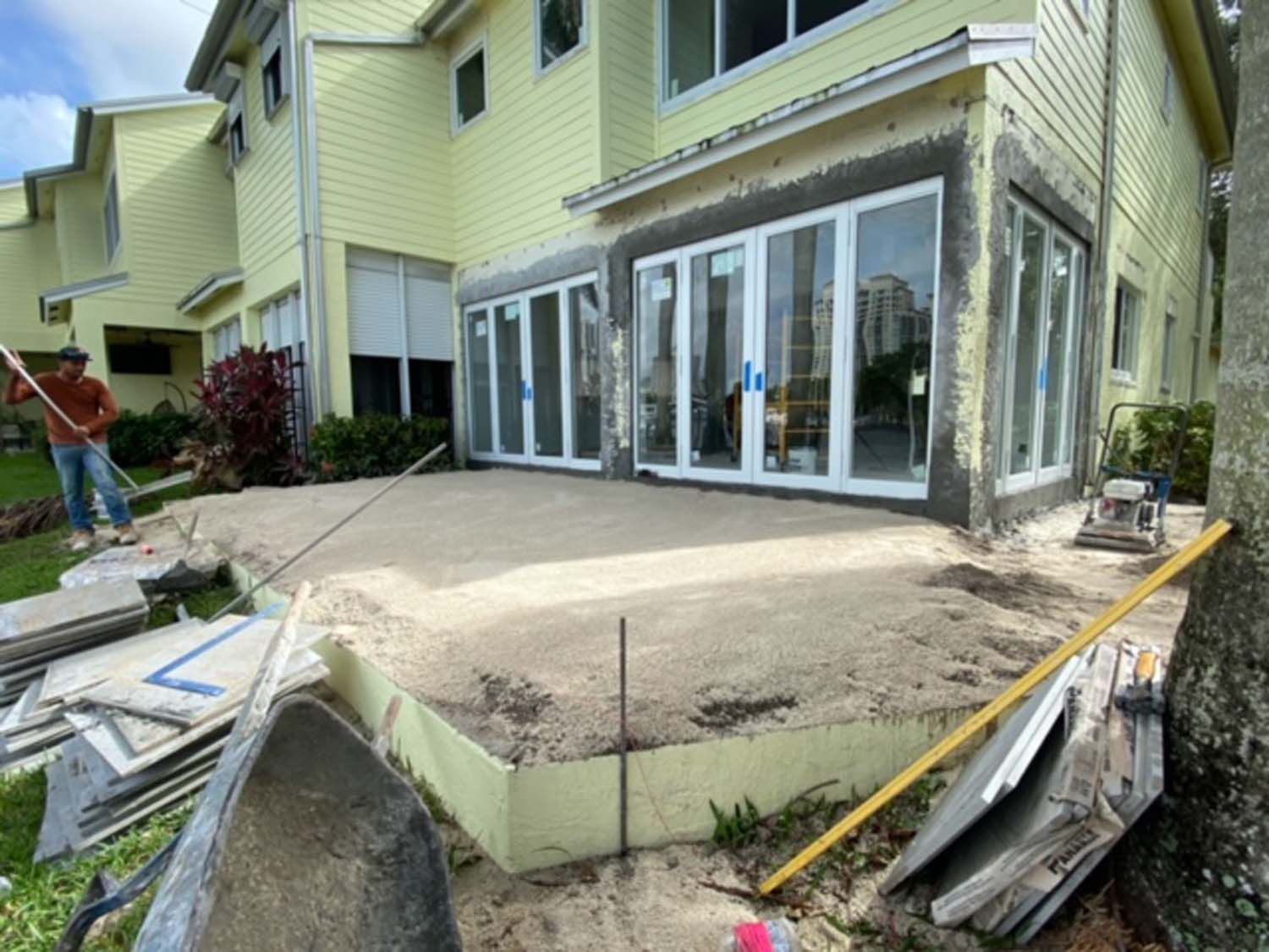 A man is working on a patio in front of a house.